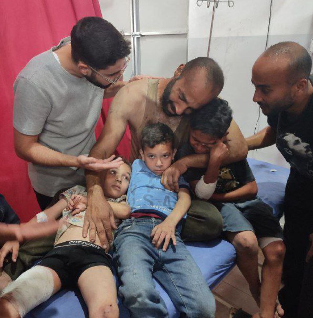 A wounded father embraces his three wounded children, after the occupation bombed a house for the "Y