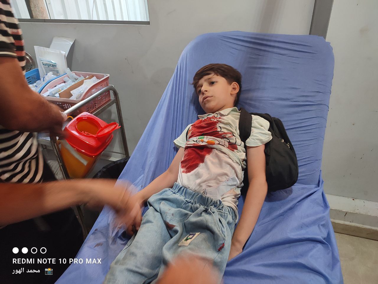 He carried his bag on his back .. The moment a child was transferred after he was bombed by the occu